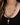 A close-up of a person wearing a layered necklace set. The set includes a gold chain with a key pendant and charm, a gold chain with a pink and yellow scallop shell pendant, and a chain with a small pink heart charm