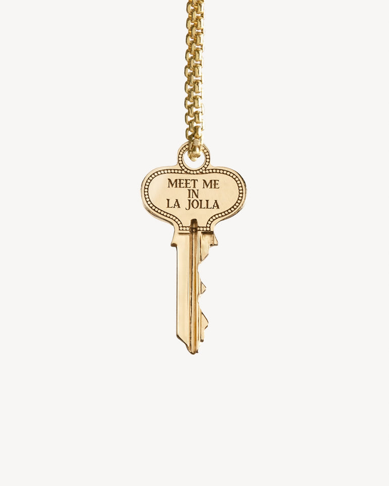 Gold key spinning on a chain engraved with 'Meet Me in La Jolla' on one side