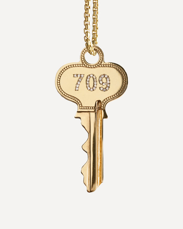 Gold key spinning on a necklace with '709' in diamonds on one side and ‘Meet Me on Dune Road’ engraved on the other side